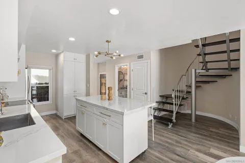 a large white kitchen with lots of counter space and chandelier