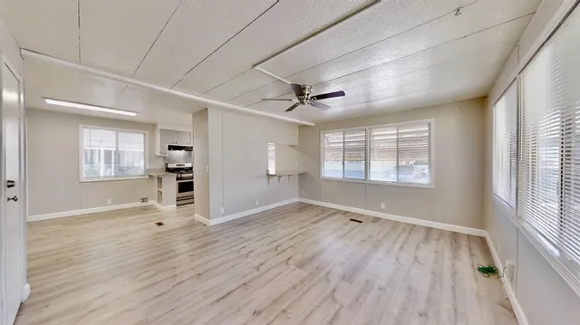 a view of a big room with wooden floor and a ceiling fan