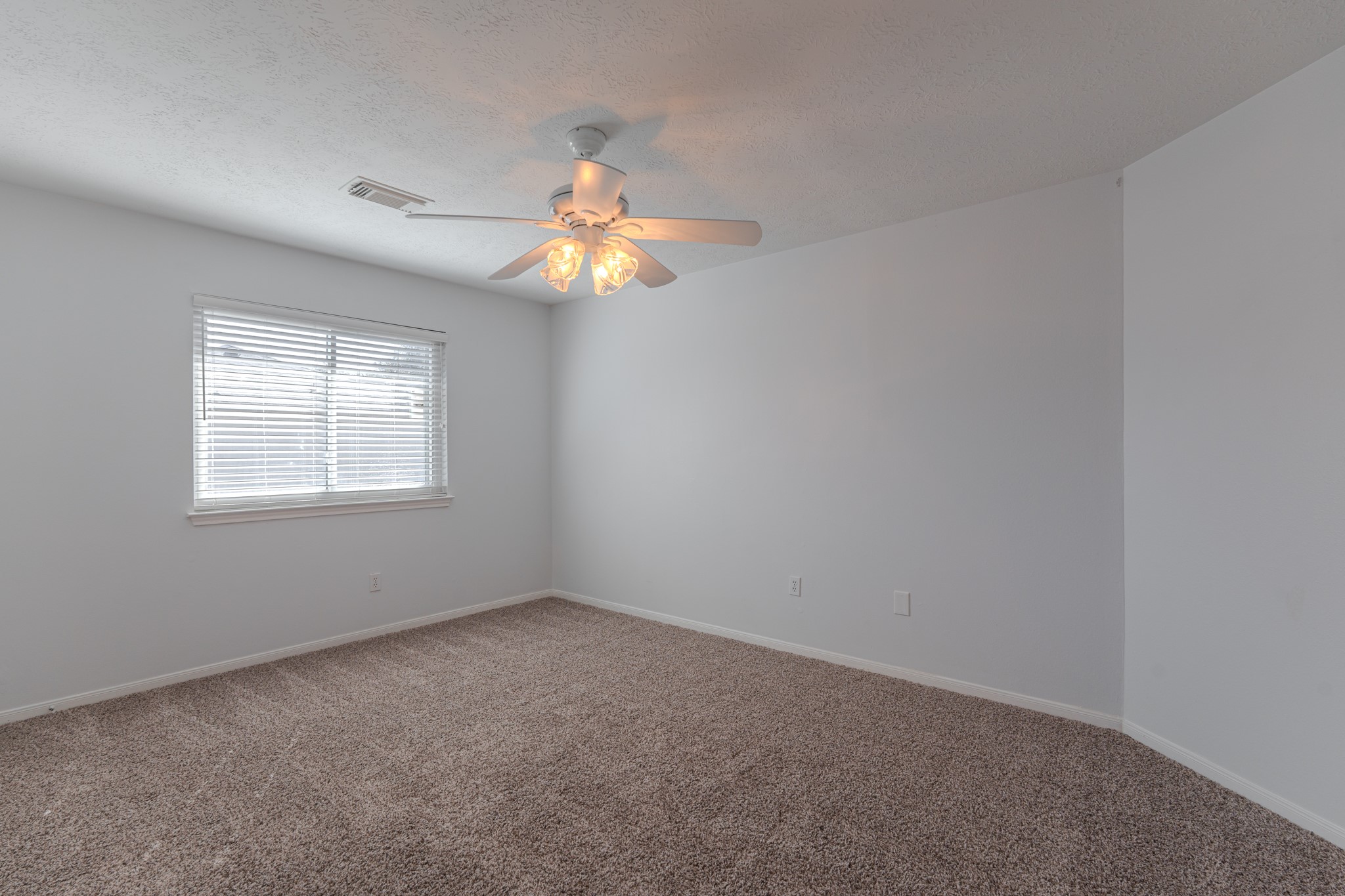 10347 Mist Lane Houston, TX 77070 - Photo 27 of 32 an empty room with windows and chandelier fan