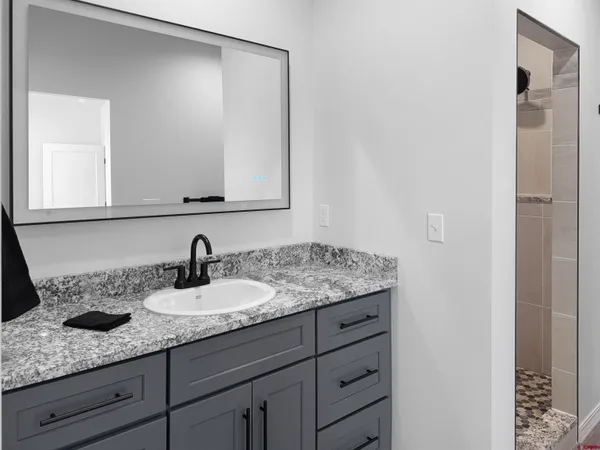 a bathroom with a granite countertop sink and a mirror