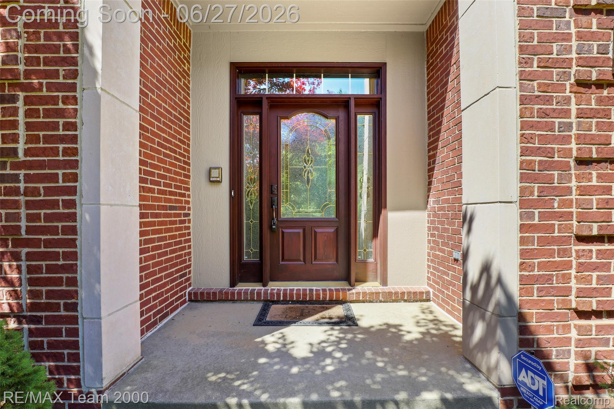 1248 Lasalle Road Canton, MI 48187 - Photo 14 of 67 Brick facade with stone accents featuring a wood-panel entry door with decorative glass, flanked by coordinating sidelights and a transom window
