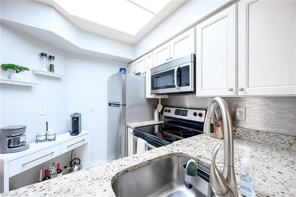 a kitchen with stainless steel appliances kitchen island granite countertop a sink stove and refrigerator