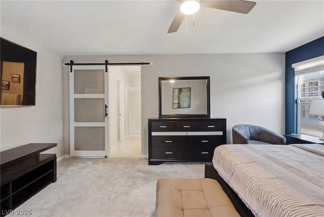 1921 Miller Ridge Avenue North Las Vegas, NV 89031 - Photo 18 of 26 This spacious bedroom features a ceiling fan, a sliding barn door, and a large window.
