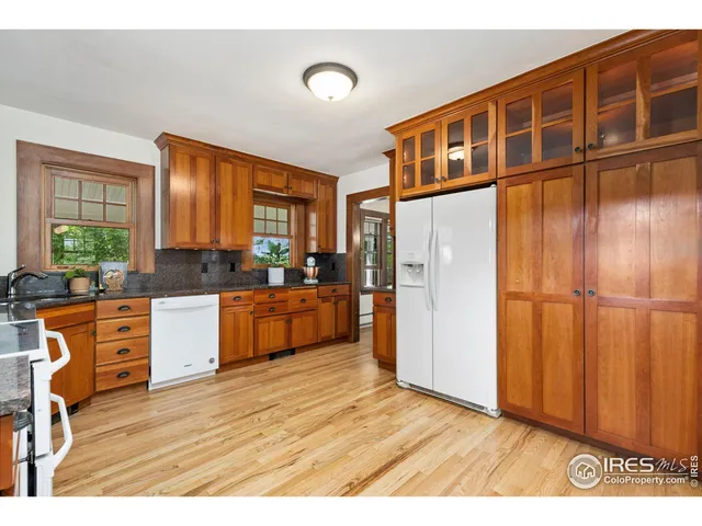 a kitchen with stainless steel appliances granite countertop a refrigerator a oven a sink with wooden cabinets and wooden floor