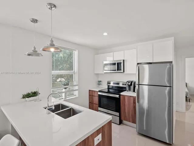 a kitchen that has a refrigerator a stove a sink and dishwasher with wooden floor