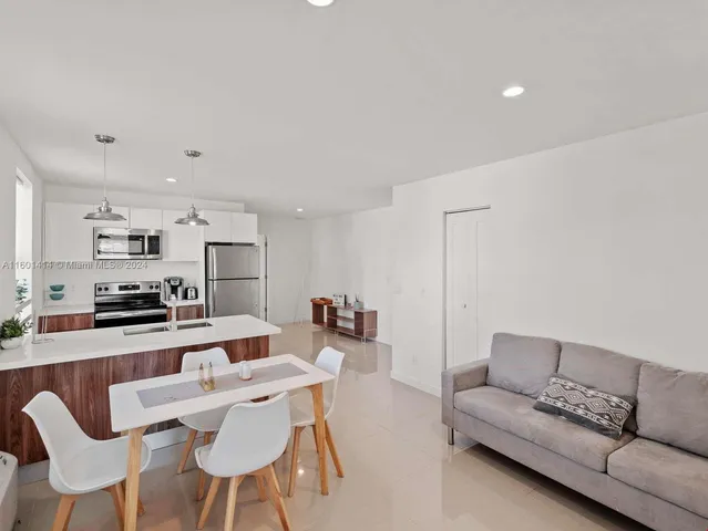 a living room with stainless steel appliances a dining table and chairs