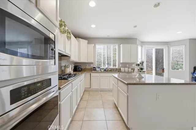 a large white kitchen with stainless steel appliances granite countertop a stove a sink and a refrigerator