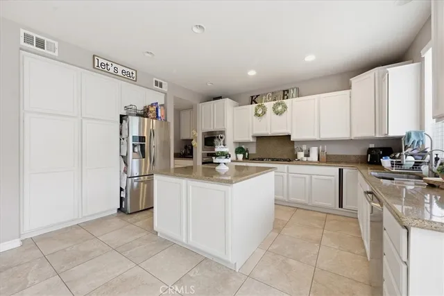 a kitchen with stainless steel appliances granite countertop a refrigerator and a stove top oven