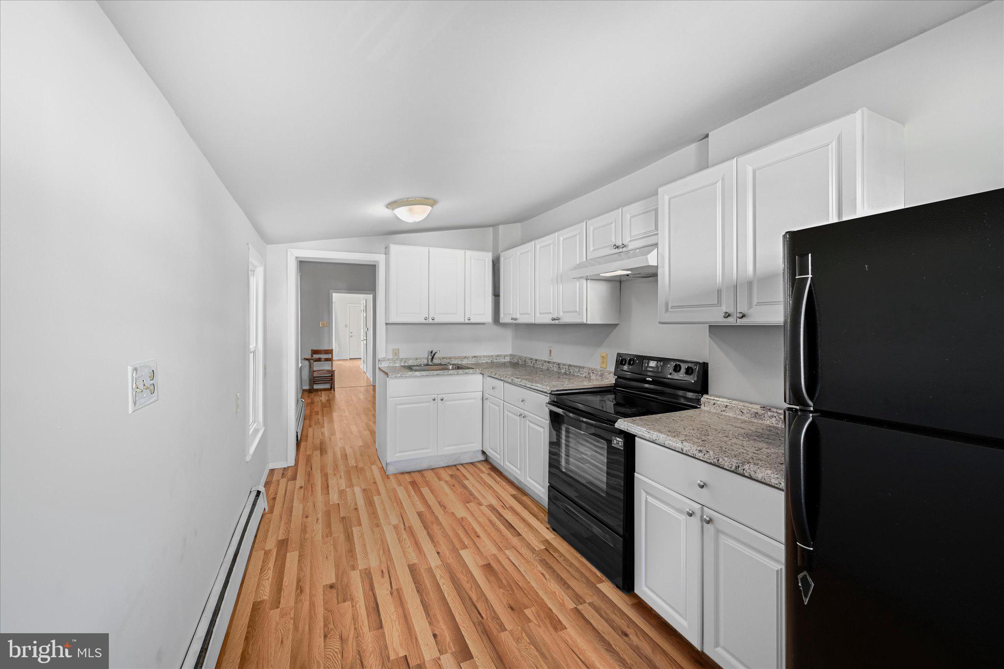 1042 Locust Street Reading, PA 19604 - Photo 10 of 28 a kitchen with a sink a refrigerator a stove top oven and wooden floor