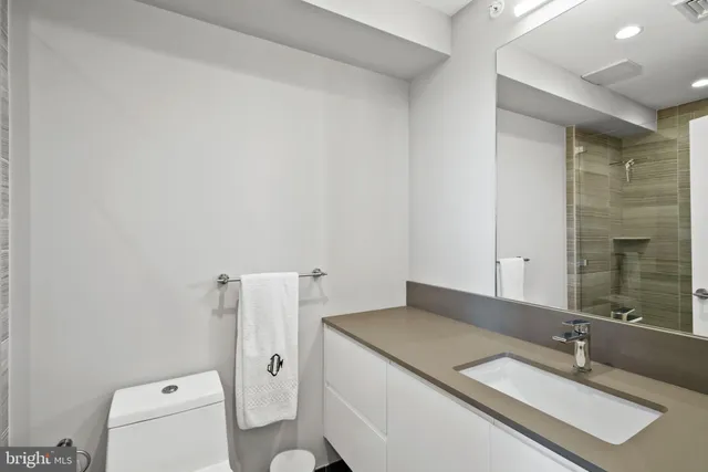 a bathroom with a granite countertop sink and a toilet