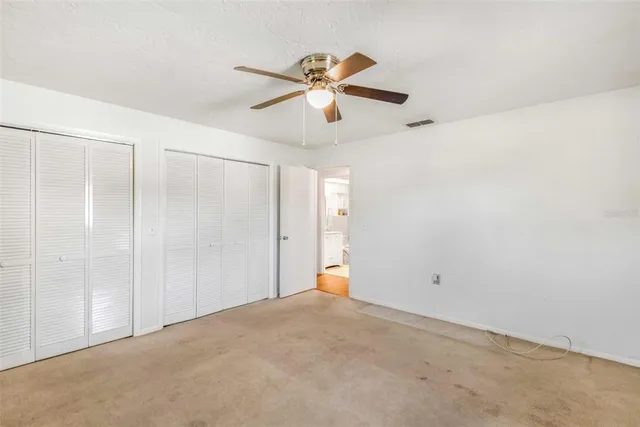an empty room with a window and a fan