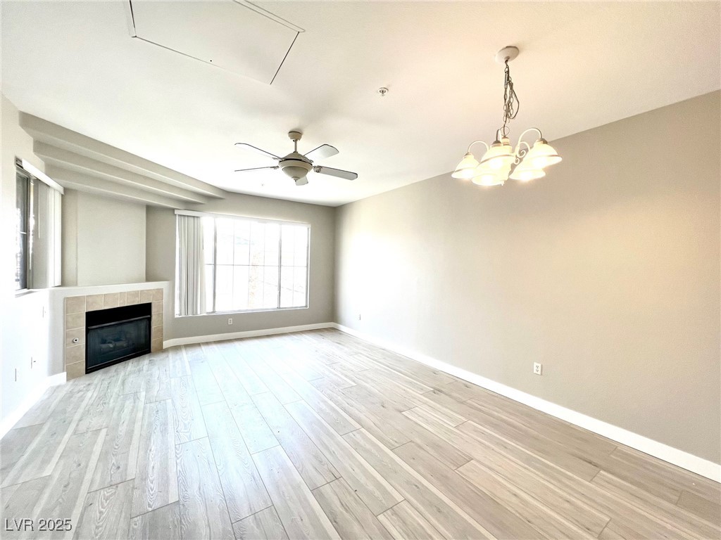 7135 South Durango Drive, Unit 304 Las Vegas, NV 89113 - Photo 2 of 11 Unfurnished living room with light wood-type flooring, a ceiling fan, a tile fireplace, and attic access