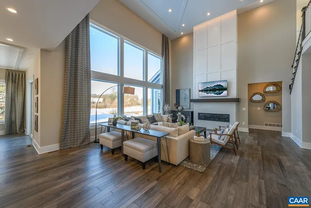 a living room with fireplace furniture wooden floor and a large window