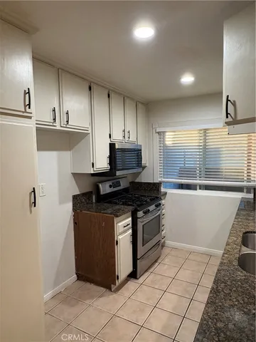 a kitchen with granite countertop a stove a sink and a refrigerator