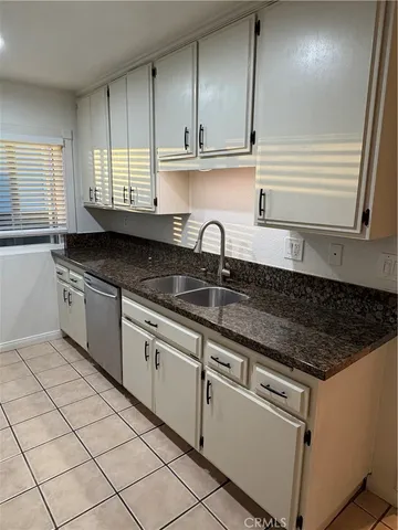 a kitchen with granite countertop a sink a stove and cabinets