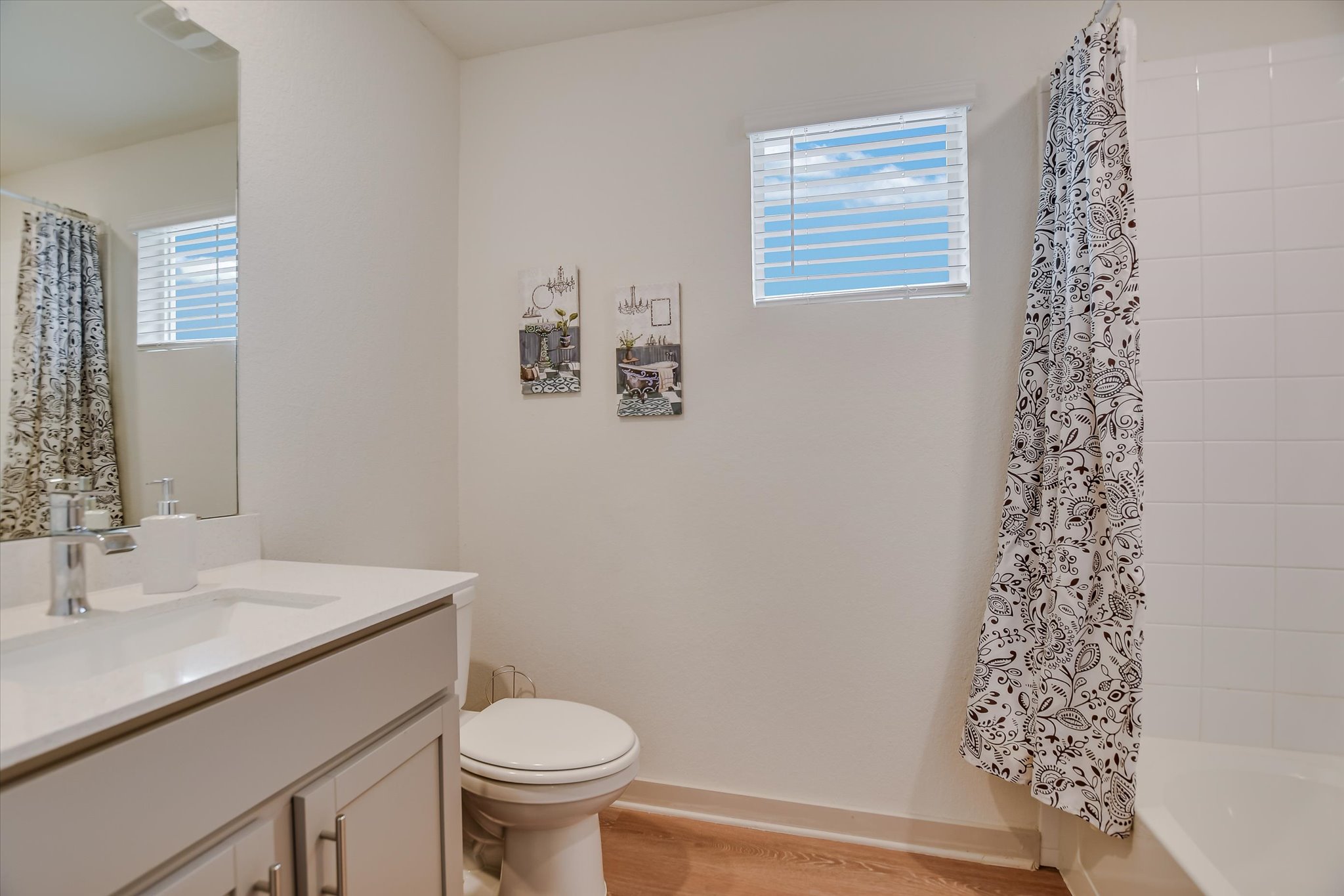 105 Merrick Road Georgetown, TX 78628 - Photo 13 of 23 A well-lit bathroom features a vanity, toilet, and a tiled shower with a decorative curtain.