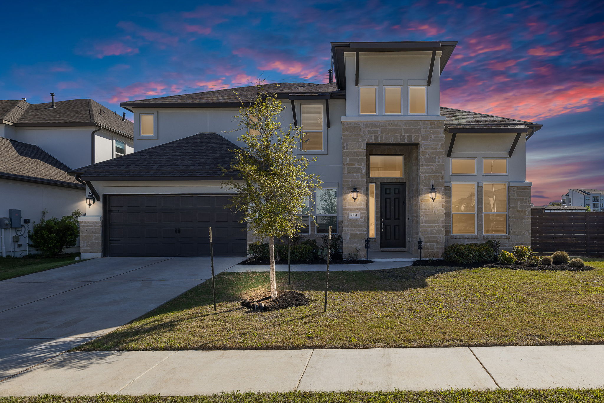604 Spindrift Lane Leander, TX 78641 - Photo 29 of 32 Modern home featuring stone siding, an attached garage, concrete driveway, stucco siding, and roof with shingles
