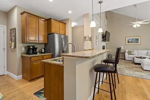 a kitchen with kitchen island granite countertop wooden cabinets and a refrigerator