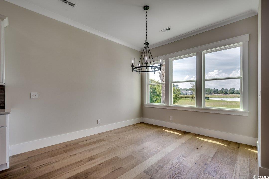 404 Plantation Oaks Drive Myrtle Beach, SC 29579 - Photo 13 of 29 Unfurnished dining area with baseboards, a chandelier, crown molding, and light wood-style floors