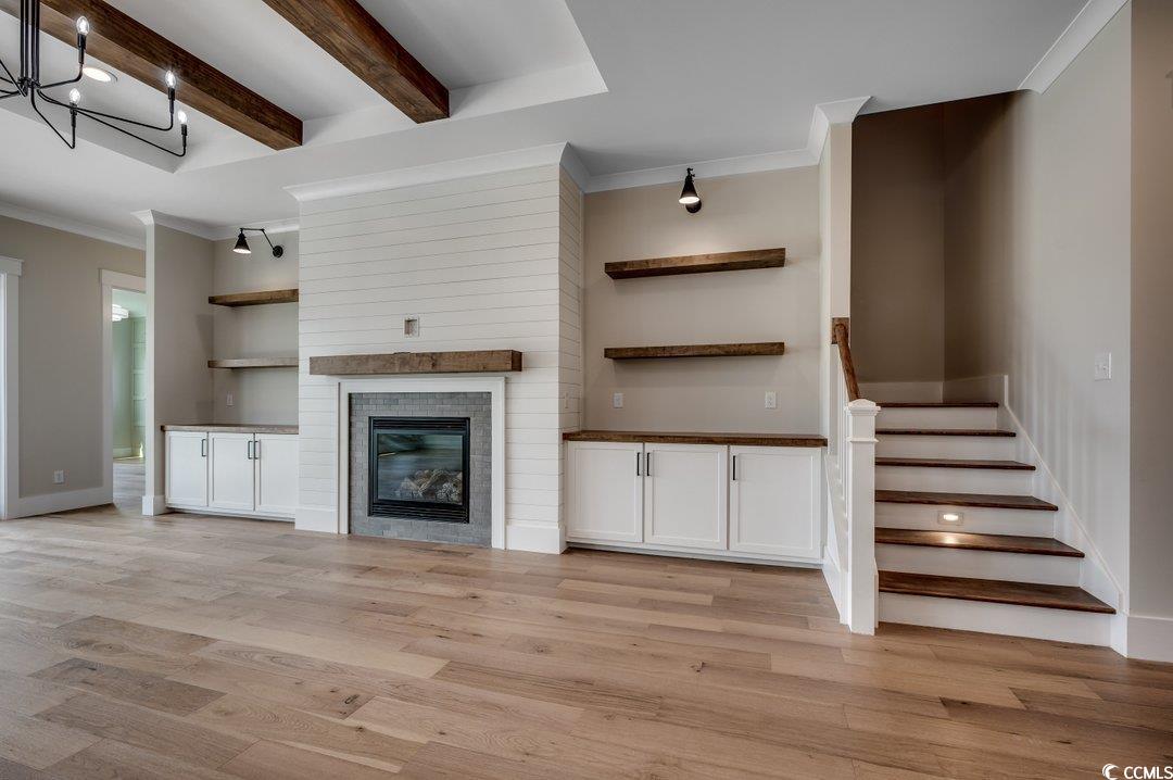 404 Plantation Oaks Drive Myrtle Beach, SC 29579 - Photo 5 of 29 Unfurnished living room with ornamental molding, light wood finished floors, beamed ceiling, stairway, and a large fireplace