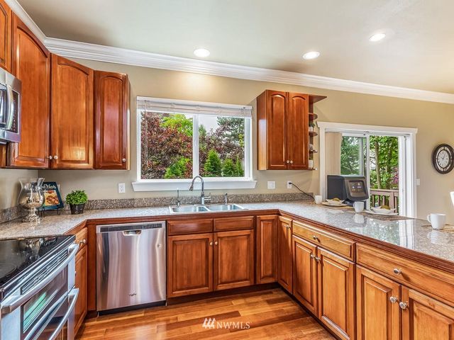 a kitchen with stainless steel appliances granite countertop a sink and wooden cabinets