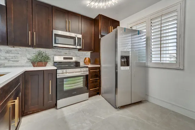 a kitchen with stainless steel appliances granite countertop a refrigerator and a stove top oven