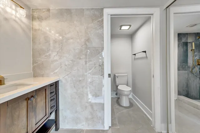 a bathroom with a granite countertop sink toilet and shower