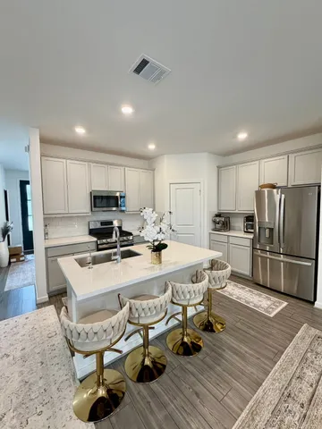 a large kitchen with a table chairs refrigerator and wooden cabinets