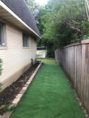 a view of a backyard with wooden fence and a bench
