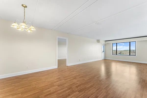 a view of empty room with wooden floor and chandelier