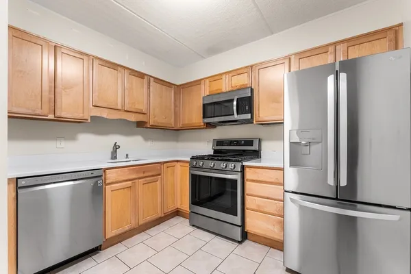 a kitchen with stainless steel appliances granite countertop a refrigerator stove a sink and dishwasher with white cabinets