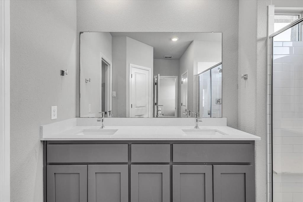 1402 Pleasanton Road Cleburne, TX 76033 - Photo 20 of 36 Dual vanity with gray cabinetry, white countertops, and chrome fixtures