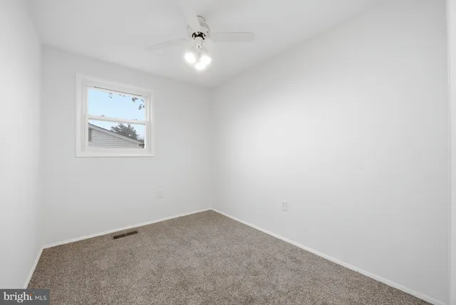 an empty room with a ceiling fan and window