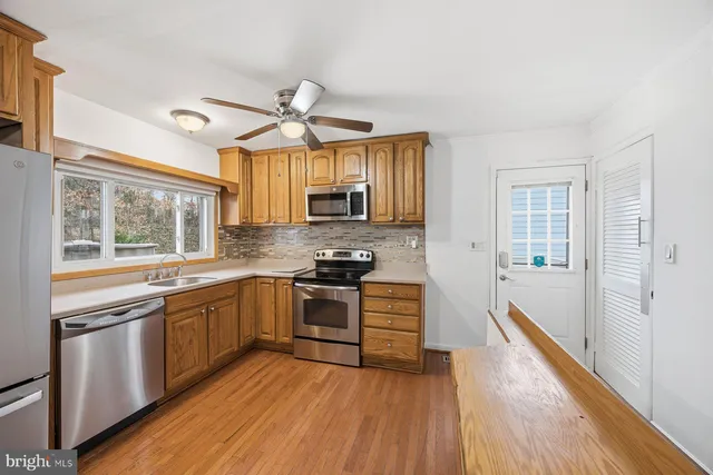 a kitchen with stainless steel appliances granite countertop hardwood floor sink stove and wooden cabinets