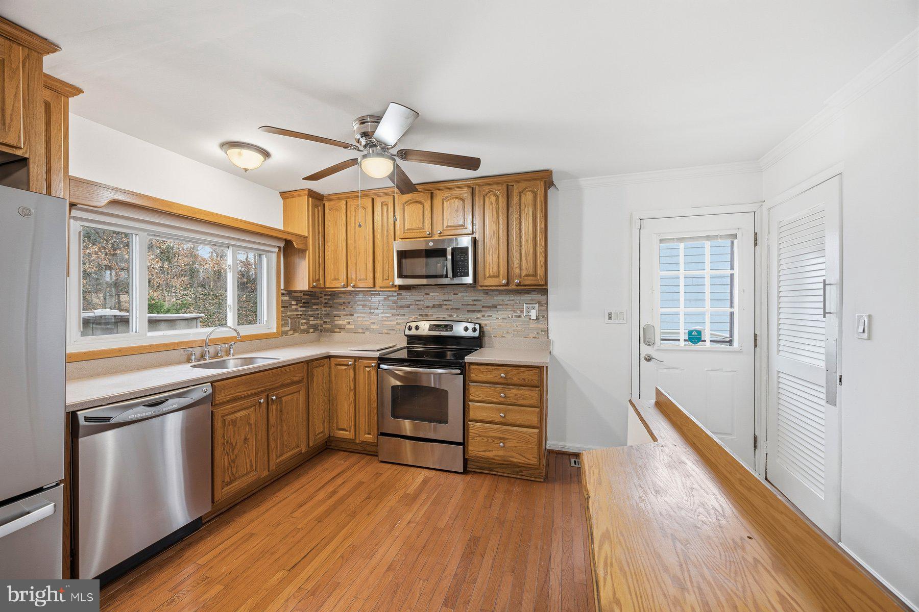 341 Dameron Street South Laurel, MD 20724 - Photo 9 of 32 a kitchen with stainless steel appliances granite countertop hardwood floor sink stove and wooden cabinets