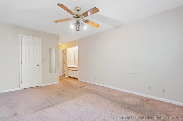 an empty room with chandelier fan and windows