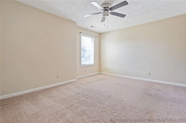 an empty room with a window and a fan