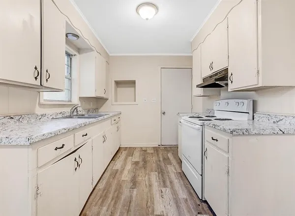 a kitchen with granite countertop a sink stainless steel appliances and white cabinets