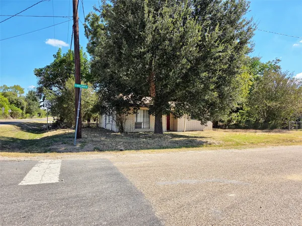 a view of a house with a yard and large trees