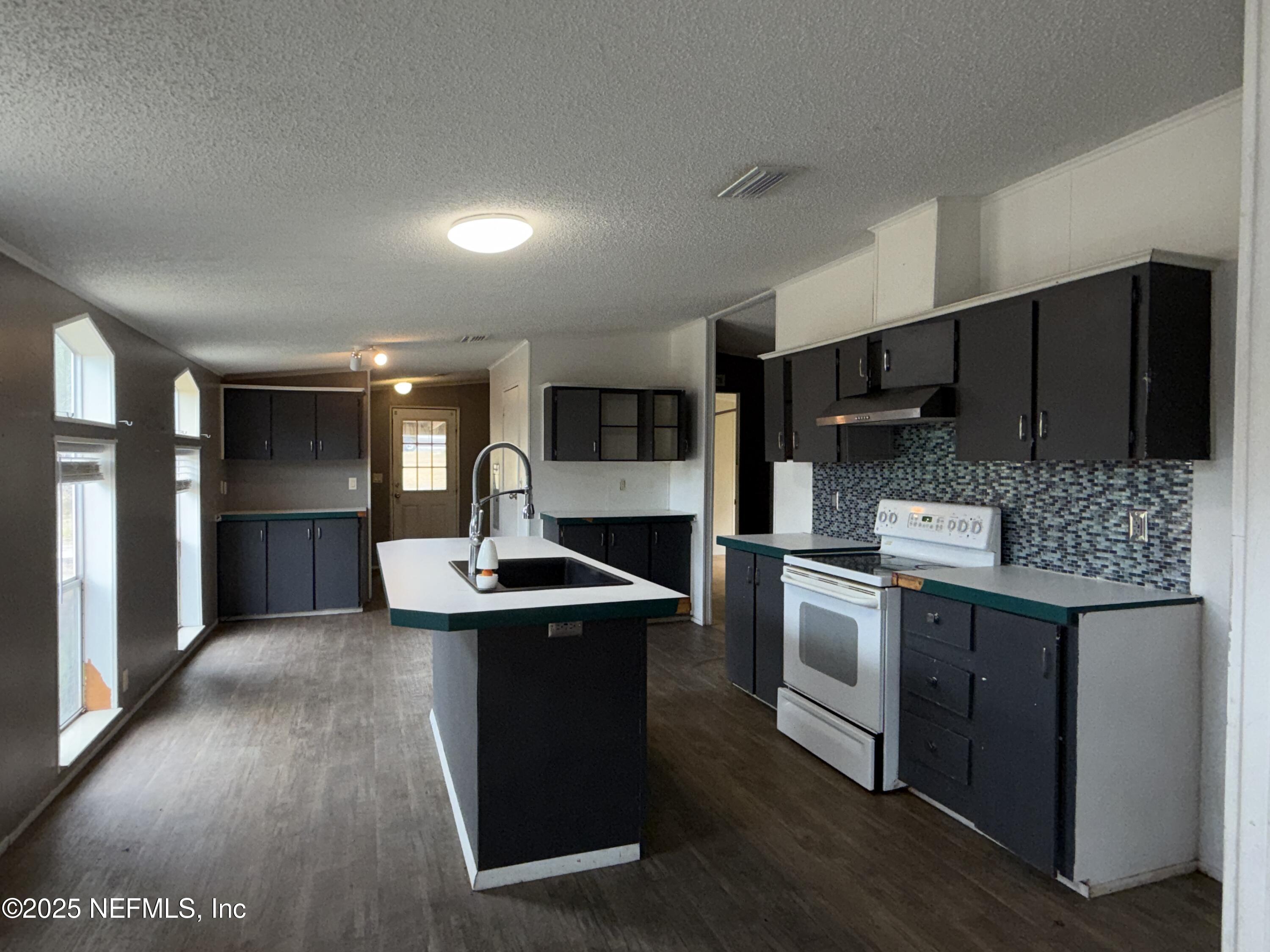 323 Incline Road Satsuma, FL 32189 - Photo 10 of 12 a kitchen with kitchen island stainless steel appliances a sink stove and refrigerator