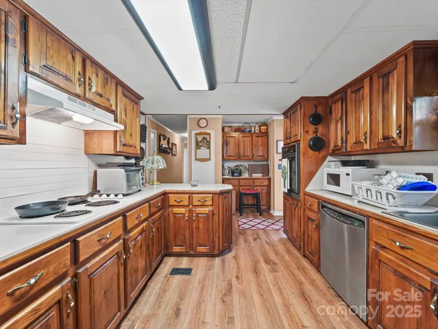 a kitchen with stainless steel appliances granite countertop a stove a sink dishwasher and cabinets with wooden floor