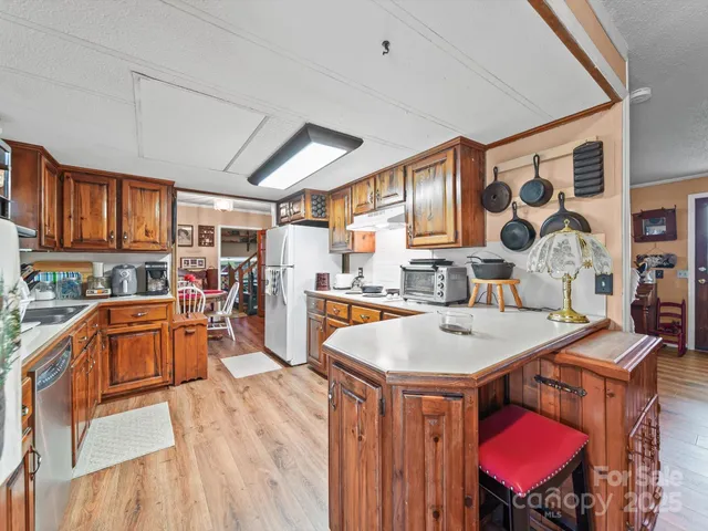 a kitchen with stainless steel appliances kitchen island granite countertop a sink dishwasher and wooden cabinets with a large window