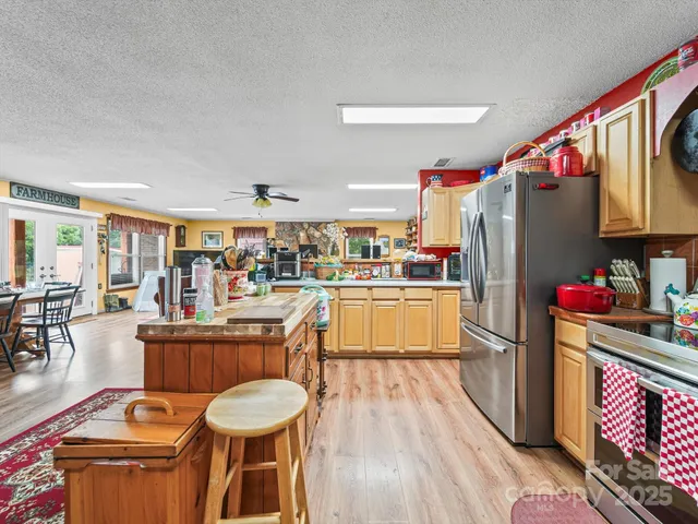 a kitchen with stainless steel appliances granite countertop a refrigerator a stove top oven and a dining table with wooden floor