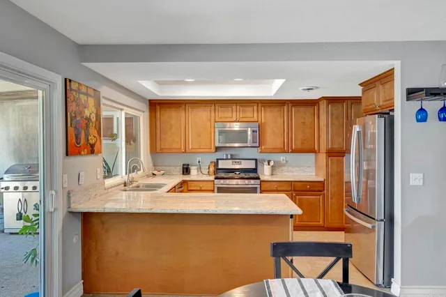 a kitchen with stainless steel appliances granite countertop a refrigerator a stove and a sink with wooden floor
