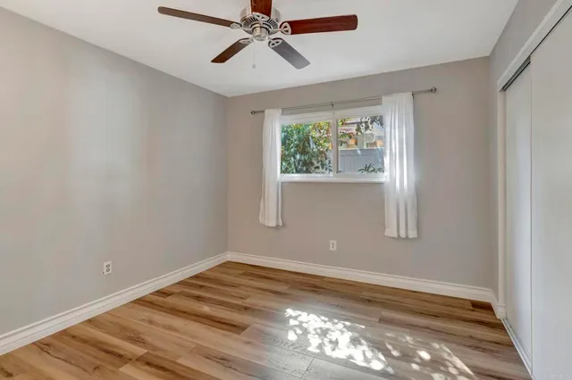 a view of empty room with wooden floor and fan