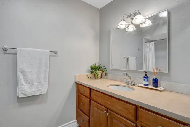 a bathroom with a granite countertop sink a light fixture and a mirror
