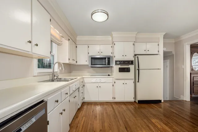 a kitchen with cabinets stainless steel appliances a sink and wooden floor