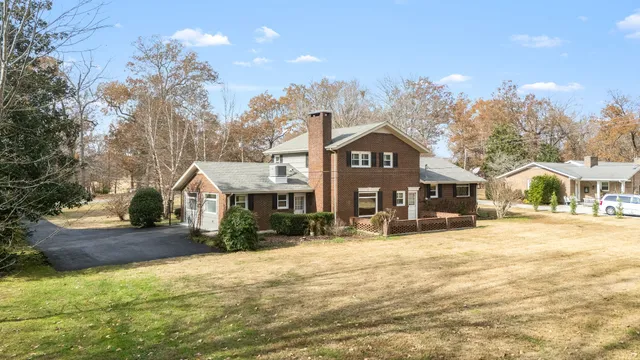 a front view of a house with a yard covered with snow and trees