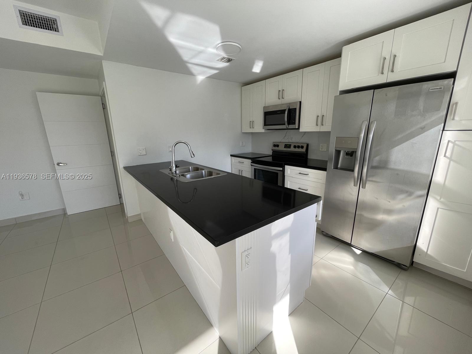 25869 Southwest 139th Court Homestead, FL 33032 - Photo 5 of 22 a kitchen with stainless steel appliances a refrigerator a sink a stove a microwave and island