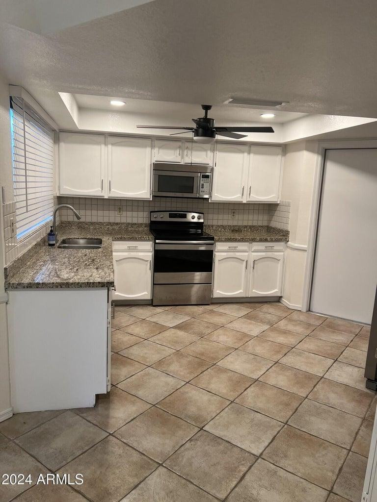 16623 North 29th Drive Phoenix, AZ 85053 - Photo 4 of 13 a kitchen with kitchen island granite countertop a sink cabinets and stainless steel appliances